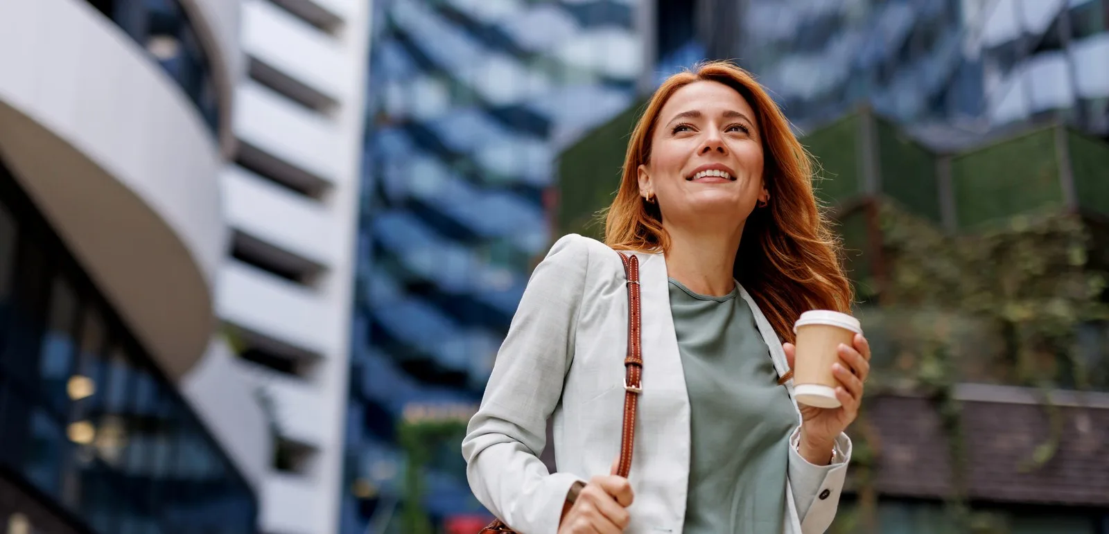 Smiling professional woman walking outdoors with a coffee